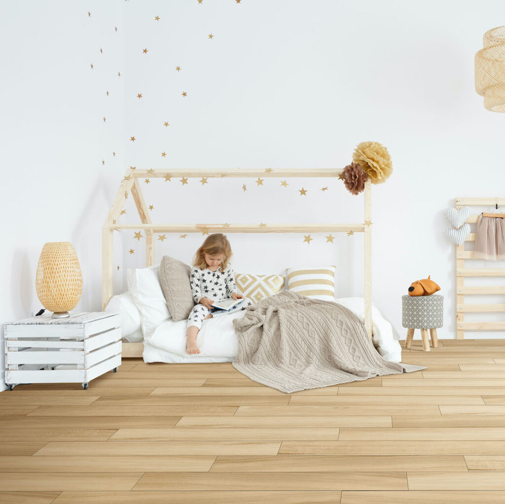 Little girl sitting on her bed in white scandinavian bedroom